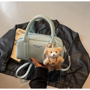 Close-up of light blue lychee pattern bowling bag with cute brown bear charm detail