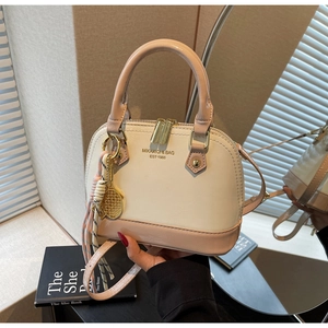 Detail of shell-shaped handbag with tennis racket charm and brand logo on leather