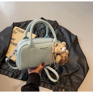 Close-up of light blue lychee pattern leather bowling bag with cute bear charm and strap