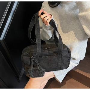 Dettaglio della borsa boston in denim nero lavato con texture e mini ciondolo a borsa