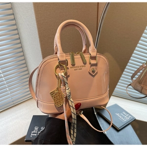 Detailed macro of pink shell bag featuring glossy synthetic leather and tennis racket charm