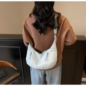Detail of light blue nylon crescent bag showing side zipper pockets and shoulder strap