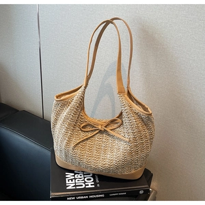 Detail of woven straw tote bag with brown leather bow and matching shoulder strap texture