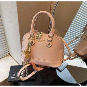 Detailed close-up of pink patent leather shell bag with golden hardware and logo