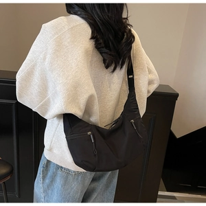 Close-up of black nylon crescent bag featuring functional dual vertical zipper pockets