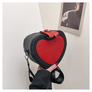 Detail view of heart-shaped crossbody bag featuring black and red contrast with silver rivets