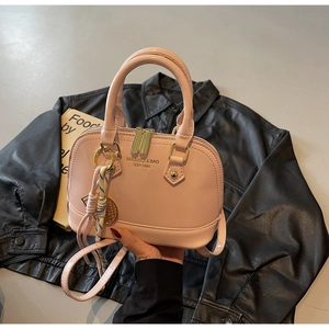 Detail of light pink shell crossbody bag with gold metal zipper and brand logo