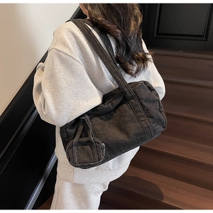 Vista dettagliata della borsa Boston in denim nero con mini pochette abbinata su modella
