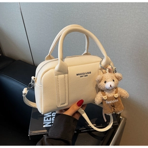 Detail of white litchi pattern leather bowling bag with cute bear charm and silver hardware