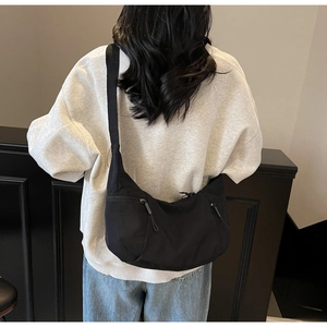 Detail of black nylon crescent bag with adjustable strap and dual zipper pockets