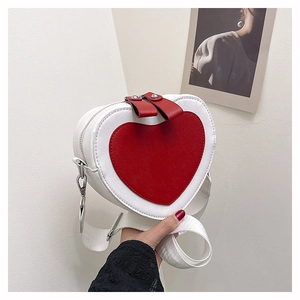 Close-up of heart-shaped crossbody bag featuring red and white PU leather and wide strap