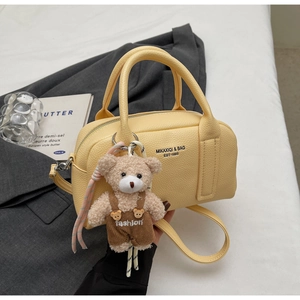Detail of yellow lychee texture leather Boston bag with a cute bear plush pendant charm