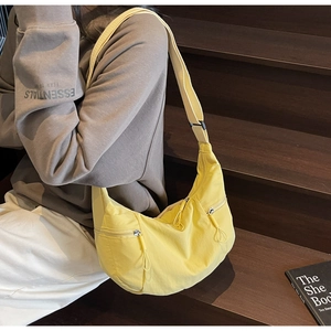 Detail of a bright yellow nylon dumpling bag with adjustable strap and zip pocket