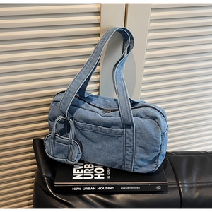 Dettaglio della borsa in denim blu con mini pochette e base di libri fashion
