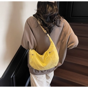 Rear view of a bright yellow nylon crescent crossbody bag on a model at a staircase