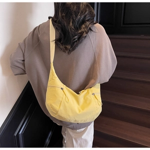 Detailed view of the yellow crescent crossbody bag showing double zipper pockets and strap