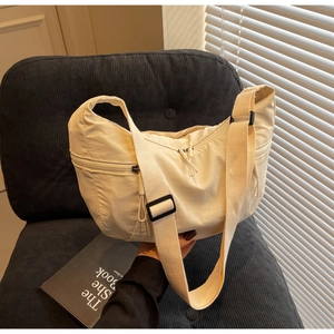 Detail view of cream nylon dumpling bag with adjustable strap and smooth zipper closure