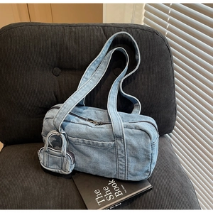 Dettaglio della borsa a spalla in denim azzurro con mini astuccio e cerniera su sedia