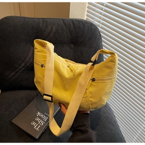 Close-up of bright yellow nylon crescent bag with multi-zipper pockets on corduroy chair