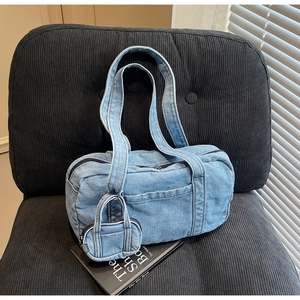 Dettaglio della borsa a spalla in denim azzurro con mini pochette e ampi spallacci su seduta