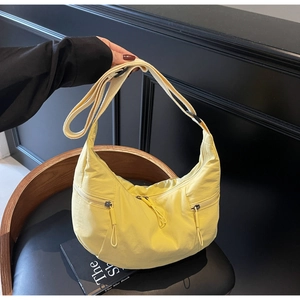 Detail of vibrant yellow dumpling bag featuring dual front zipper pockets and wide strap