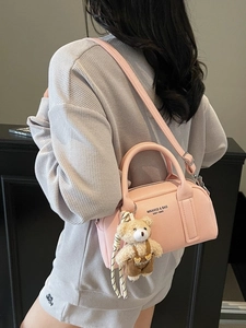 Pink textured leather bowling bag with cute bear charm shown on a fashion model