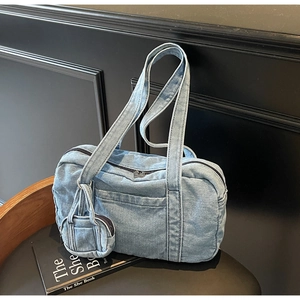 Dettaglio della borsa a spalla in denim azzurro con mini portamonete su vassoio in legno