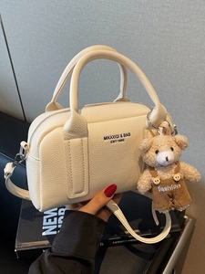 Chic beige lychee grain bowling handbag with cute bear charm and adjustable shoulder strap