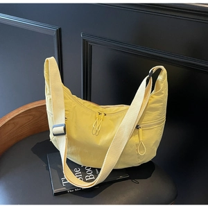 Detail of yellow nylon crescent bag with wide strap and circular ring zipper pulls