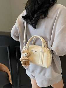 Chic beige lychee leather Boston bag with plush bear charm and adjustable shoulder strap