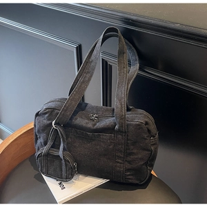 Dettaglio della borsa a spalla in denim nero con mini portamonete e zip in metallo
