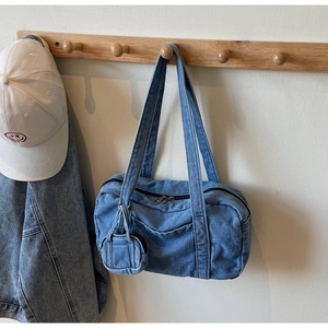 Dettaglio borsa in denim con mini portamonete appesa a un gancio di legno