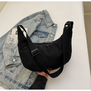 Detail of black nylon crescent bag showing texture, wide strap and side hidden zipper