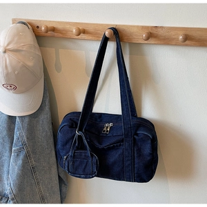 Dettaglio della borsa a tracolla in denim blu scuro con ciondolo mini portafoglio