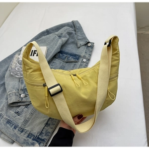 Detail of light yellow nylon dumpling bag with adjustable strap and zip pockets