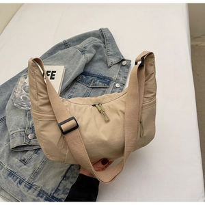 Detailed macro view of khaki nylon crescent bag with adjustable wide strap and zipper detail