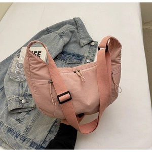 Pink nylon crescent bag detail showing side pocket and adjustable shoulder strap
