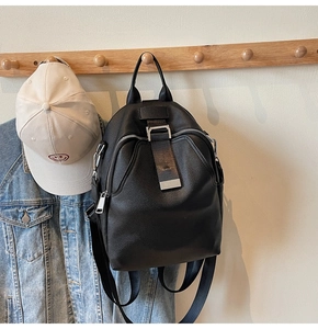 Detail of black leather backpack with silver metal buckles hung in a casual setting