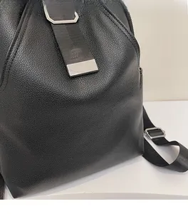 Close-up of black lychee grain leather texture and silver buckle on the backpack strap