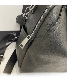 Close-up of smooth silver zippers and lychee grain leather texture on a black backpack