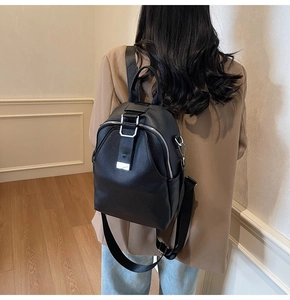 Detailed back view of model wearing black leather backpack with silver metallic buckle