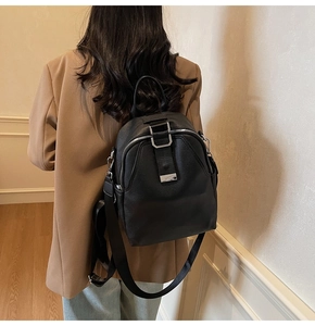 Side view of black pebble leather backpack with metal clasp on female model back