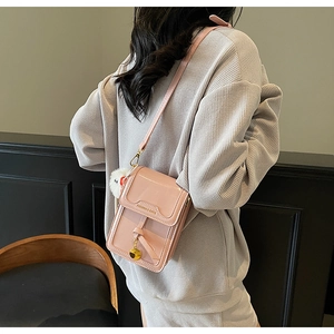 Detail of pink patent leather crossbody bag with bow decoration and white pom-pom charm