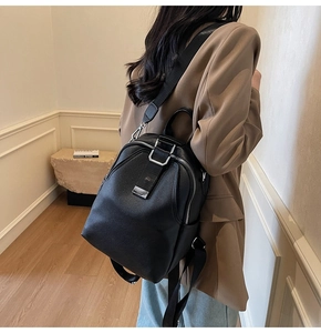 Detail of black pebbled leather backpack showing silver zippers and fabric shoulder straps