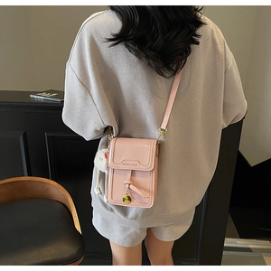 Pink glossy phone bag with adjustable strap and decorative white plush pompom charm