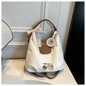 Gros plan d'un sac cabas blanc en cuir avec breloque Capybara, nœud dentelle et broderie