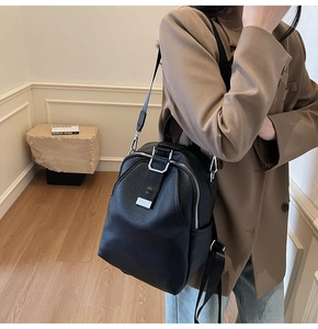 Detailed view of women's black pebble leather backpack with silver zippers and straps