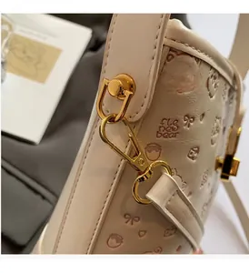 Close-up of golden metal buckle on cream leather bucket bag with bear print