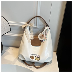 Détail des écussons brodés et du nœud en dentelle sur ce sac fourre-tout chic