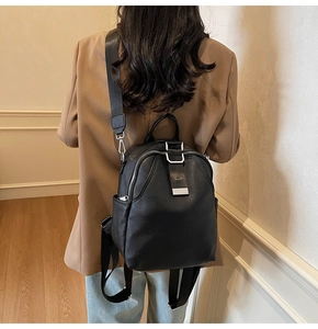 Close-up of black lychee grain leather backpack featuring silver hardware and wide straps